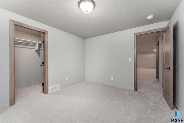 unfurnished bedroom featuring light carpet, a closet, and a textured ceiling