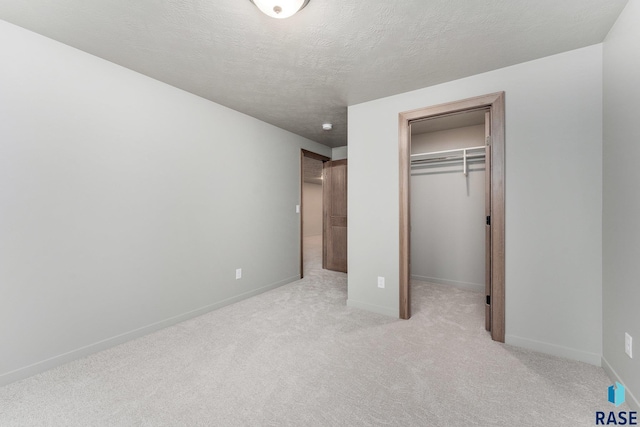 unfurnished bedroom with light carpet, a closet, and a textured ceiling