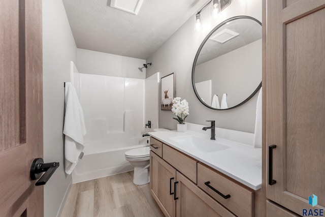 full bathroom featuring hardwood / wood-style floors, vanity, toilet, a textured ceiling, and tub / shower combination