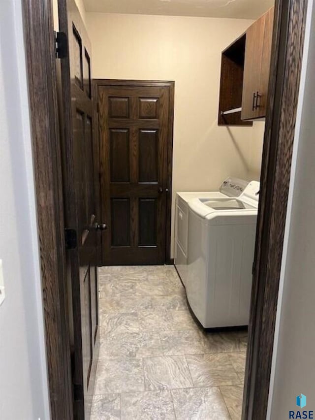 laundry area featuring light tile patterned flooring, cabinets, and washing machine and dryer