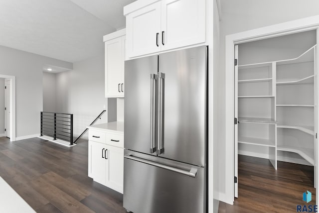 kitchen featuring baseboards, white cabinets, dark wood finished floors, high quality fridge, and light countertops