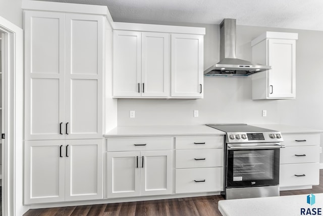 kitchen with dark wood-style flooring, white cabinets, light countertops, wall chimney range hood, and stainless steel electric stove