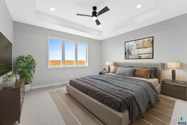 bedroom featuring carpet, a raised ceiling, and baseboards