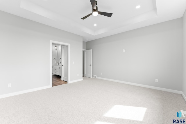 unfurnished bedroom with recessed lighting, carpet flooring, a raised ceiling, and baseboards