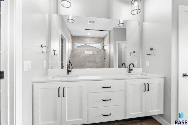 full bath with double vanity, visible vents, a sink, and tiled shower