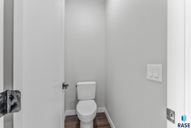 bathroom with toilet, baseboards, and wood finished floors