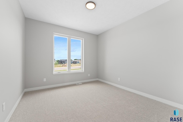 carpeted spare room featuring baseboards