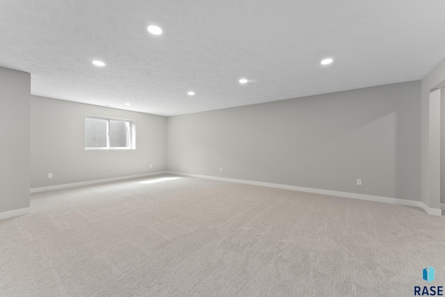 spare room with light carpet, recessed lighting, and baseboards