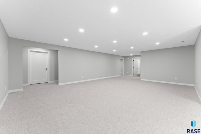 basement featuring baseboards, light carpet, and recessed lighting