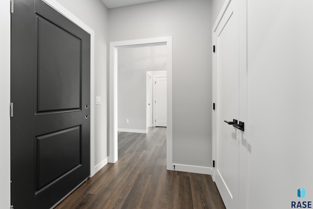 hallway with dark wood-type flooring and baseboards