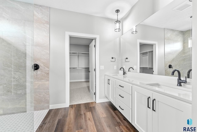 full bath featuring visible vents, walk in shower, a sink, and wood finished floors