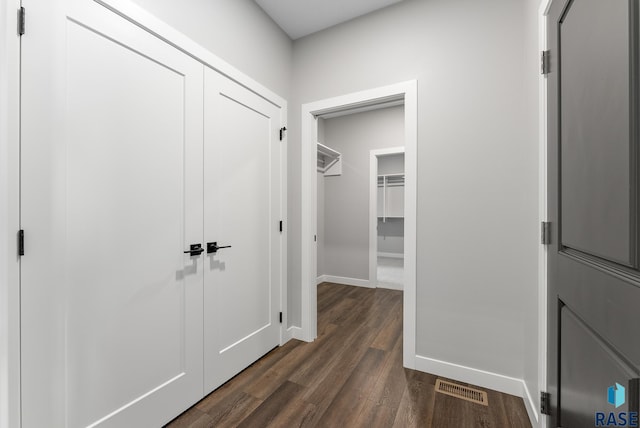 corridor featuring dark wood-style flooring, visible vents, and baseboards