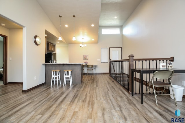 interior space featuring hanging light fixtures, kitchen peninsula, stainless steel refrigerator, and light wood-type flooring