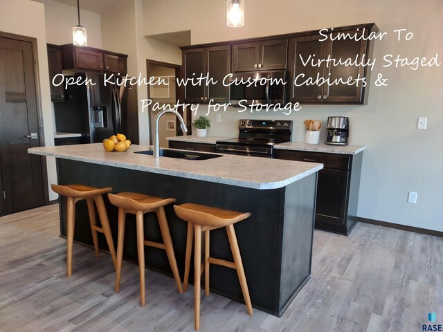 kitchen featuring a kitchen island with sink, sink, stainless steel appliances, and pendant lighting