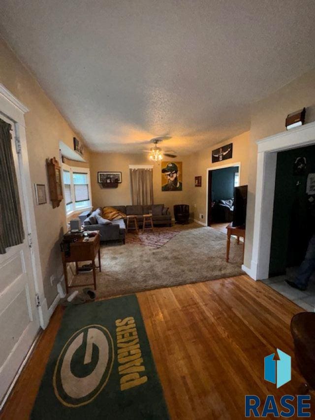 living room featuring ceiling fan, hardwood / wood-style flooring, and a textured ceiling