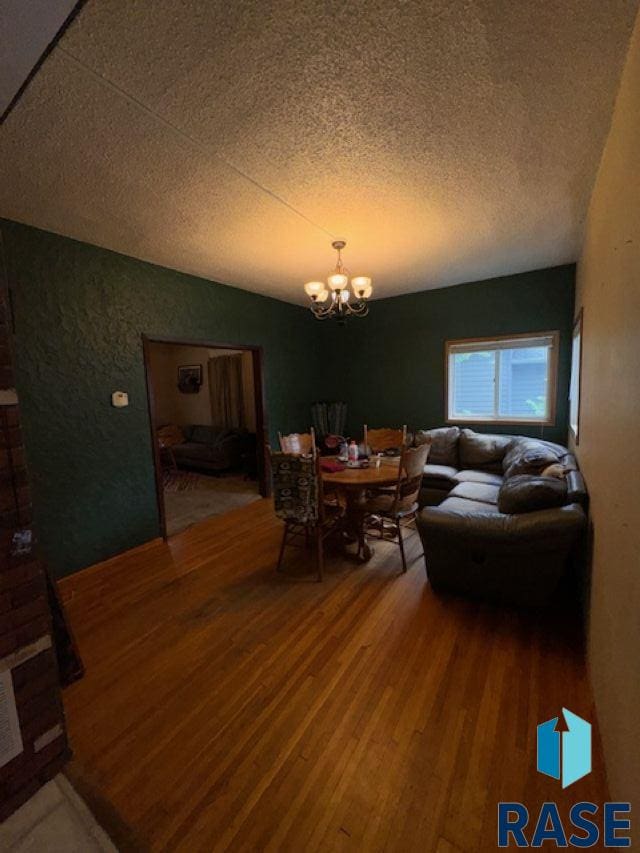 living room featuring a notable chandelier, a textured ceiling, and hardwood / wood-style flooring