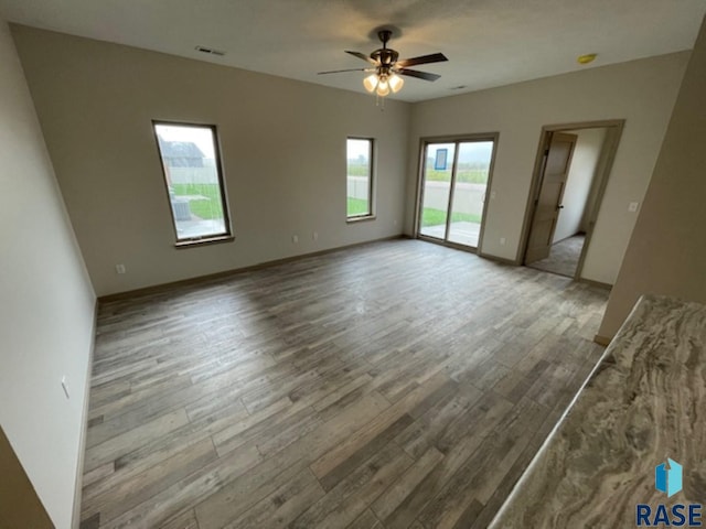 spare room with ceiling fan, hardwood / wood-style flooring, and a wealth of natural light