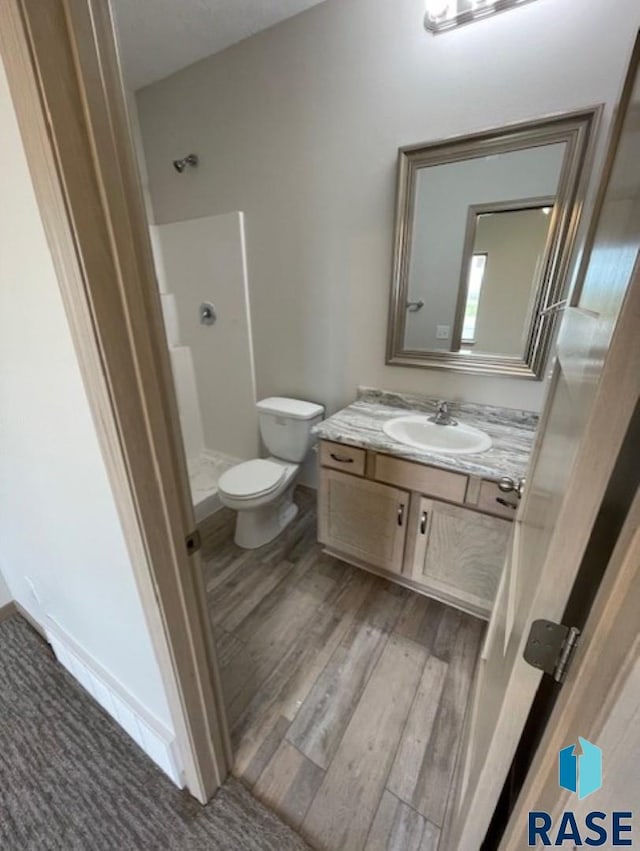 bathroom with a shower, wood-type flooring, vanity, and toilet