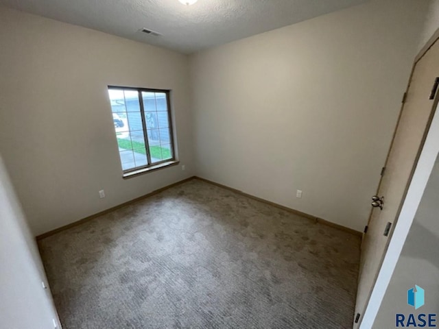 empty room with a textured ceiling and light colored carpet