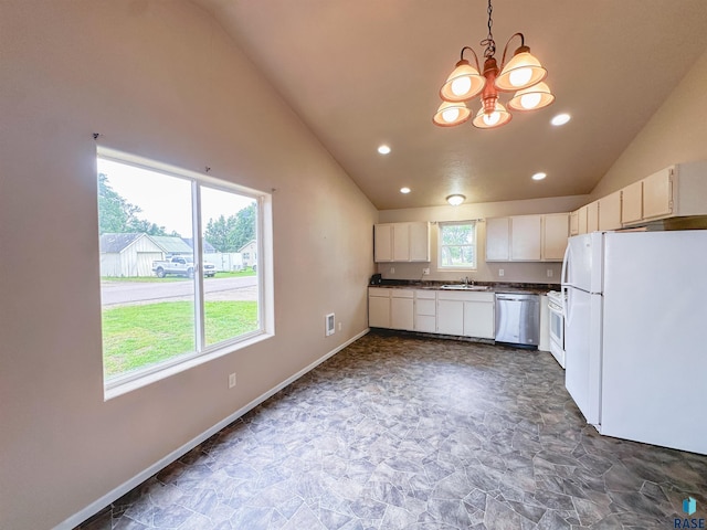 kitchen with dark tile patterned flooring, white appliances, an inviting chandelier, sink, and decorative light fixtures