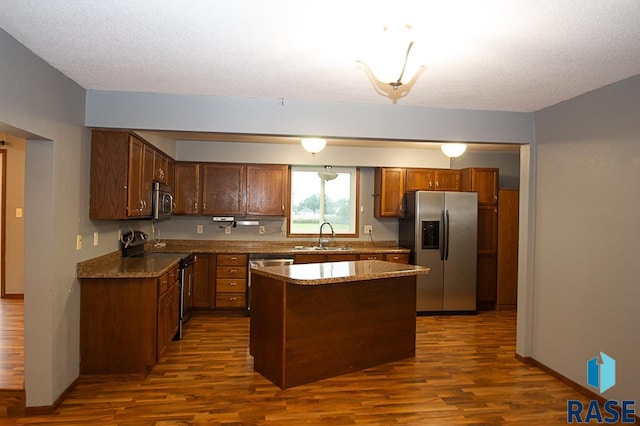 kitchen featuring sink, dark hardwood / wood-style floors, a textured ceiling, a kitchen island, and stainless steel appliances