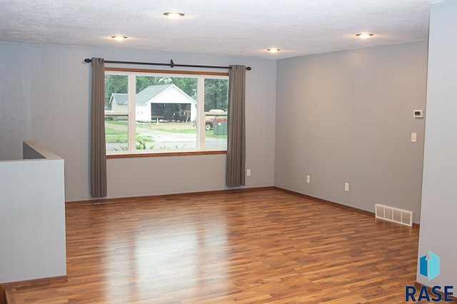 spare room featuring a textured ceiling, wood finished floors, and visible vents