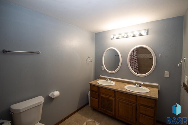 full bathroom featuring double vanity, a sink, toilet, and baseboards