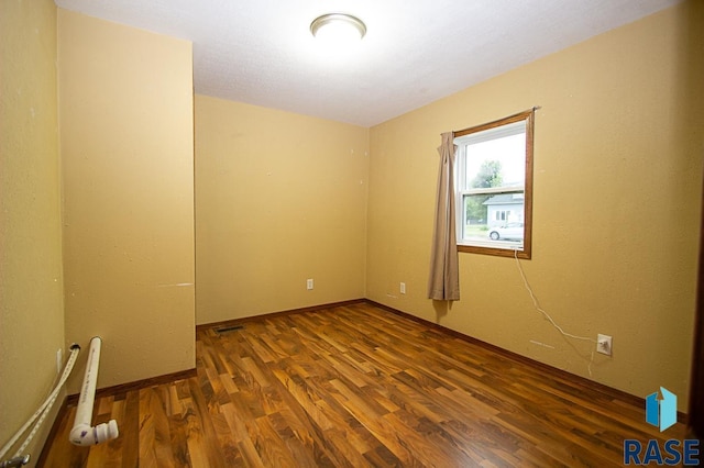 spare room with visible vents and dark wood finished floors