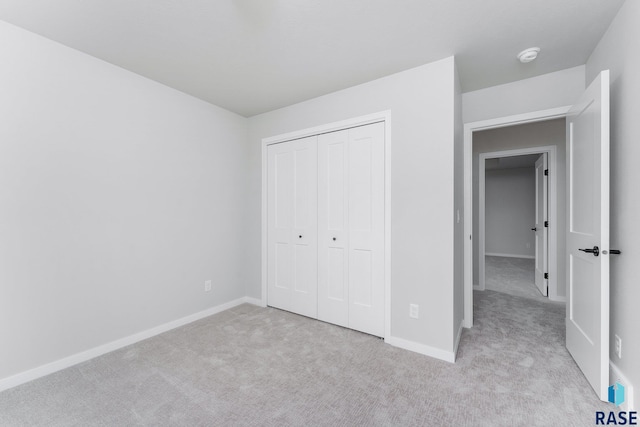 unfurnished bedroom featuring light colored carpet and a closet