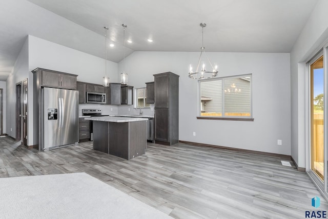 kitchen with dark brown cabinetry, a kitchen island, appliances with stainless steel finishes, light hardwood / wood-style floors, and decorative light fixtures