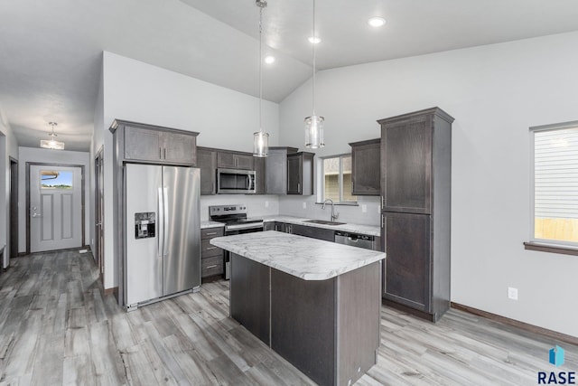 kitchen featuring a kitchen island, hanging light fixtures, light hardwood / wood-style floors, sink, and stainless steel appliances