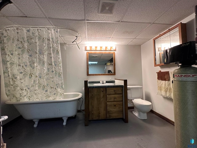 bathroom featuring toilet, a drop ceiling, concrete floors, and vanity