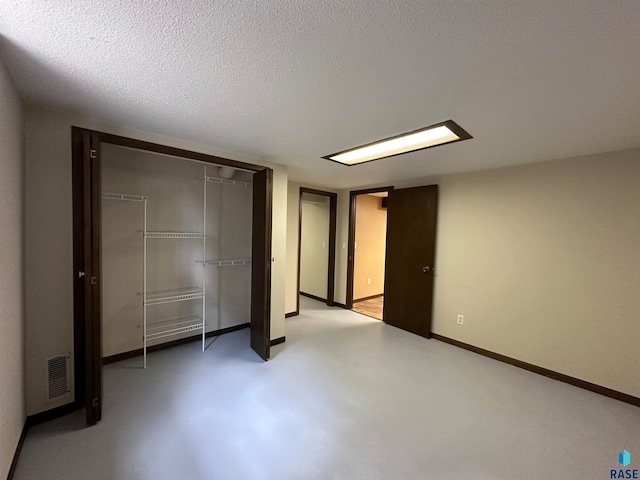 unfurnished bedroom with a closet, concrete floors, and a textured ceiling