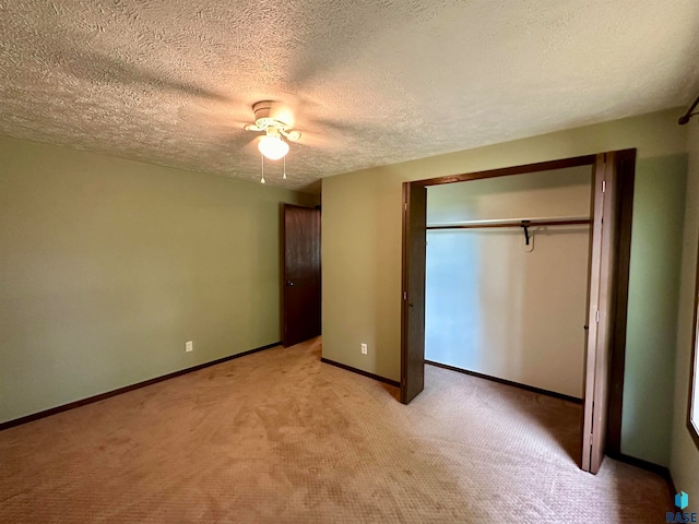 unfurnished bedroom featuring light carpet, a textured ceiling, ceiling fan, and a closet