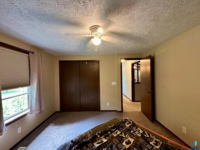 unfurnished bedroom featuring a textured ceiling, ceiling fan, a closet, and carpet floors