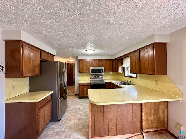 kitchen with a textured ceiling, stainless steel appliances, and sink