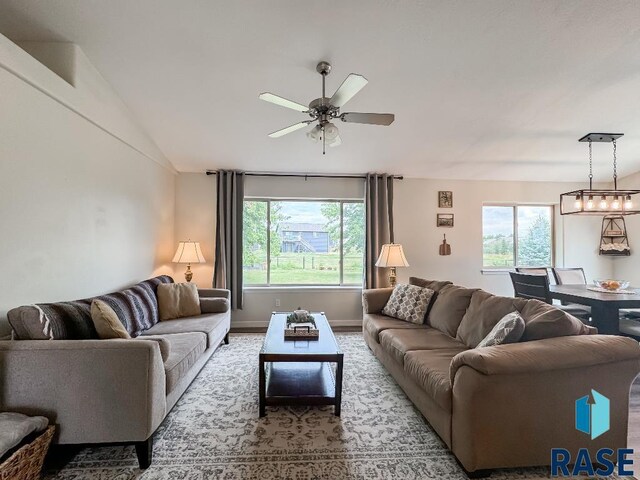 living room with vaulted ceiling, plenty of natural light, and ceiling fan with notable chandelier