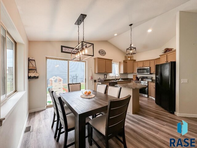 dining room featuring hardwood / wood-style floors, vaulted ceiling, sink, and a notable chandelier