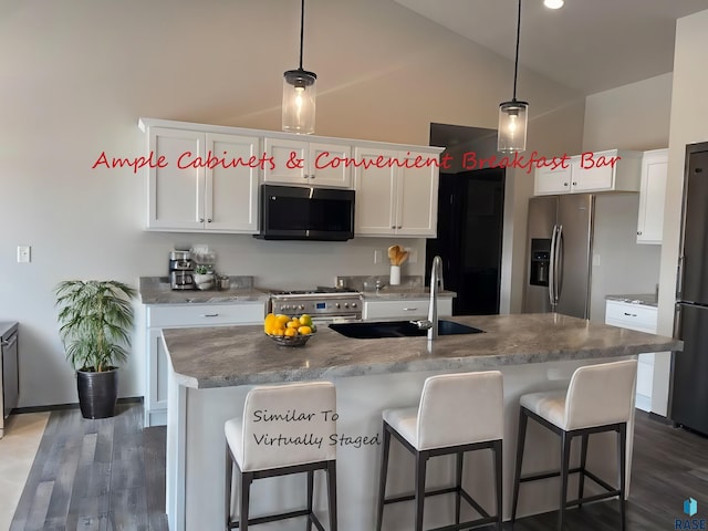 kitchen featuring a center island with sink, hanging light fixtures, appliances with stainless steel finishes, white cabinets, and vaulted ceiling