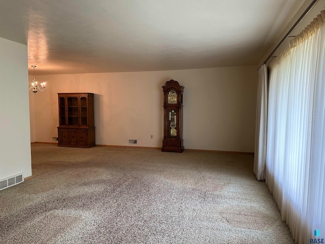 carpeted spare room with an inviting chandelier