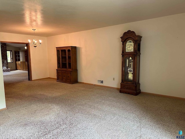 carpeted empty room featuring a chandelier