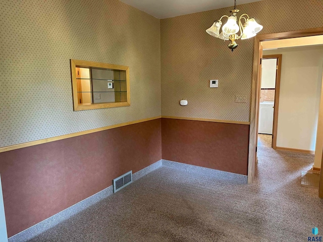 carpeted spare room with a chandelier and washer / dryer