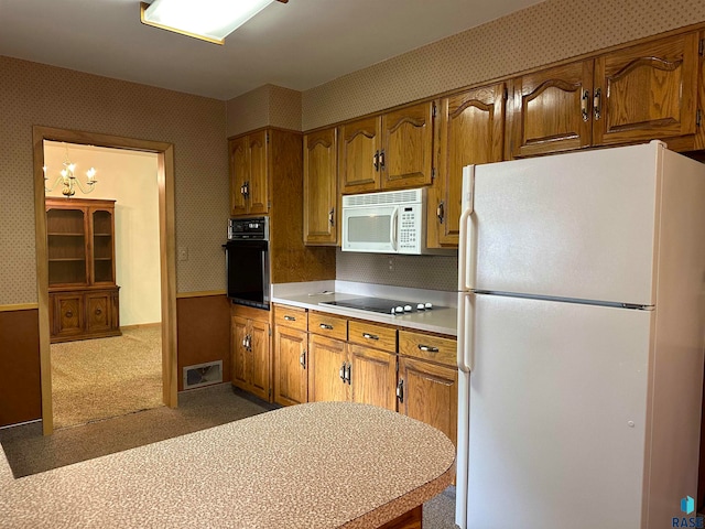 kitchen featuring carpet floors, an inviting chandelier, and black appliances