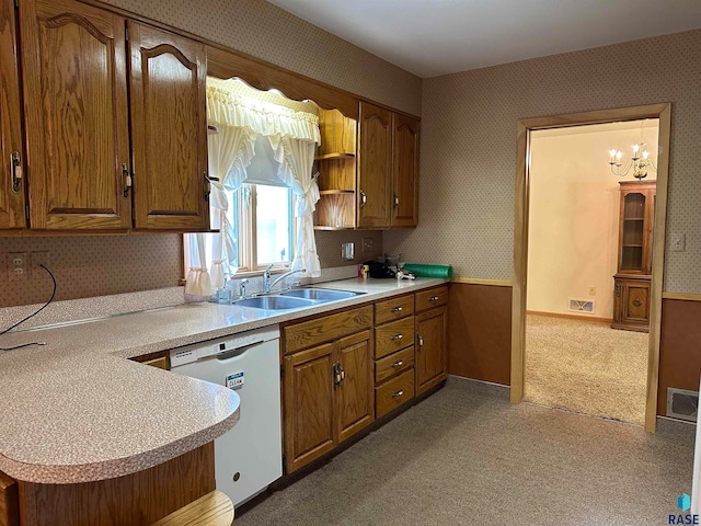 kitchen featuring carpet, sink, white dishwasher, a chandelier, and kitchen peninsula