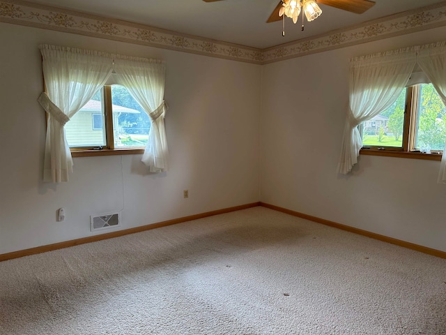 empty room featuring a wealth of natural light, carpet floors, and ceiling fan