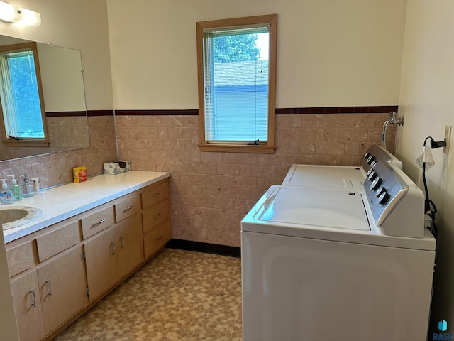 laundry room featuring light tile patterned floors, sink, independent washer and dryer, and tile walls