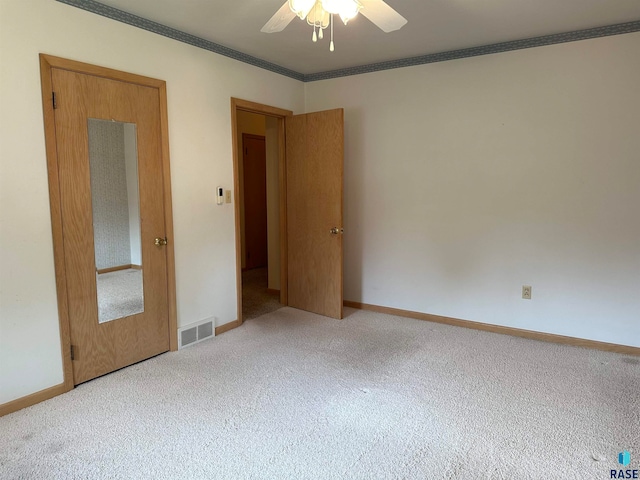 empty room featuring ceiling fan, light carpet, and ornamental molding