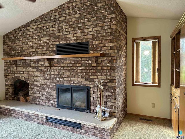 interior space with lofted ceiling, brick wall, a textured ceiling, and a fireplace