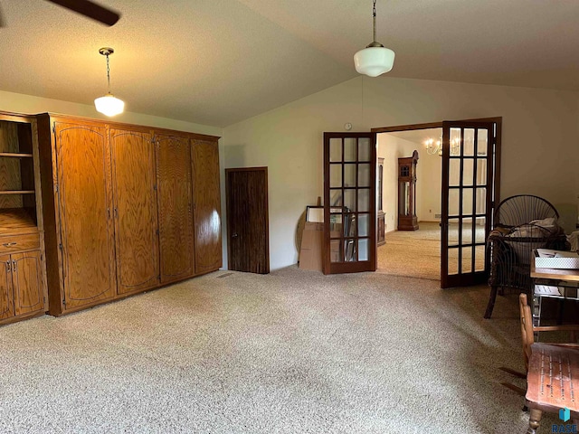 interior space featuring french doors, light colored carpet, and lofted ceiling