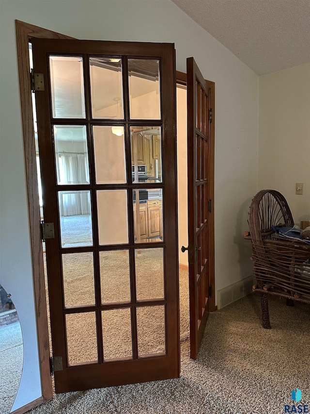 doorway to outside featuring carpet, vaulted ceiling, and a textured ceiling